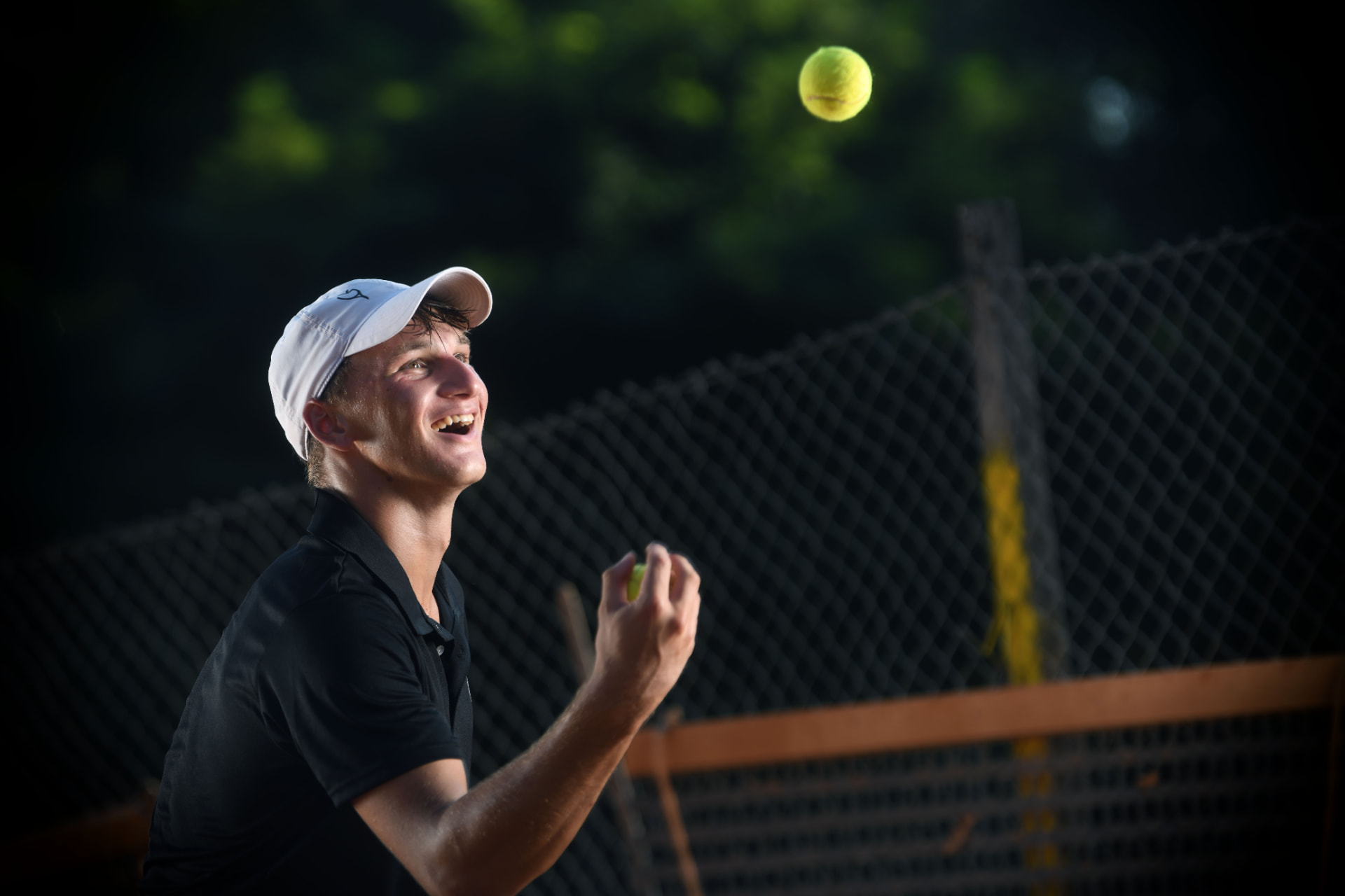 Gil Kita smiling with a tennis ball on court