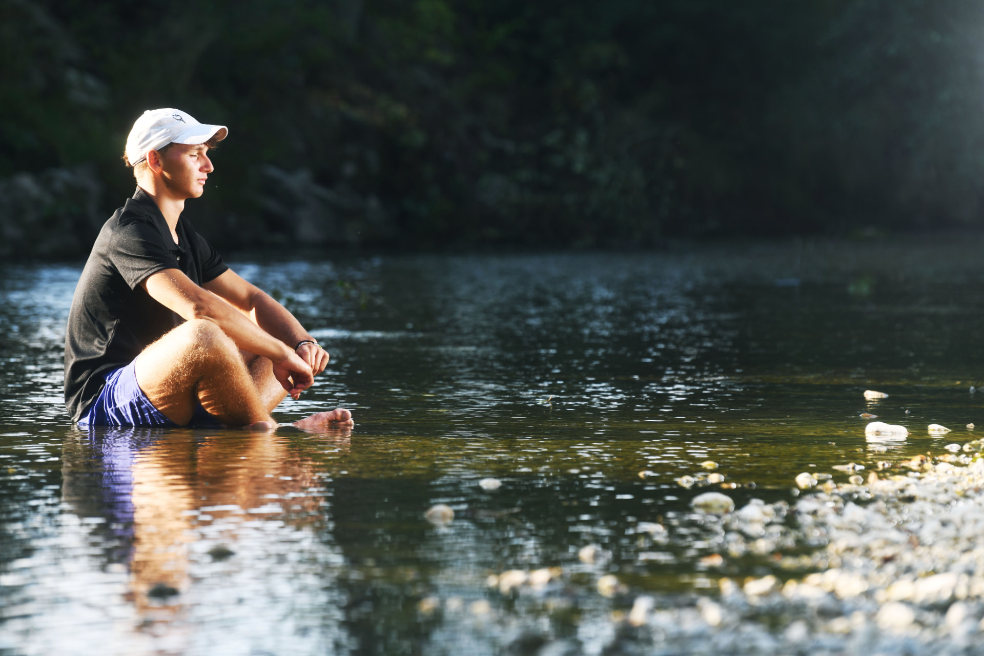 Gil Kita sitting in shallow river water